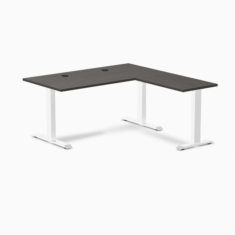 Desky Zero L-shape office desk with burnished wood laminate top, white steel frame, and grommets.