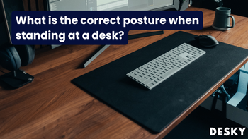What is the correct posture when standing at a desk?