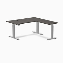 Desky L-Shape Laminate Sit Stand Desk in Burnished Wood with Gray frame and grommets.