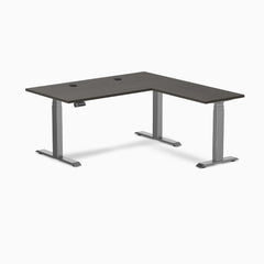 Desky L-Shape Laminate Sit Stand Desk in burnished wood with space gray frame and grommets.