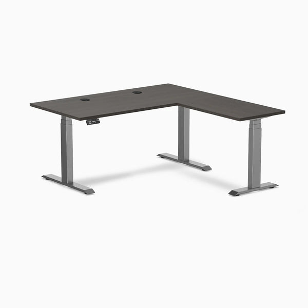 Desky L-Shape Laminate Sit Stand Desk in burnished wood with space gray frame and grommets.