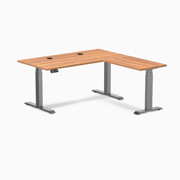 Desky L-Shape Laminate Sit Stand Desk in Prime Oak with Space Gray frame and grommets.