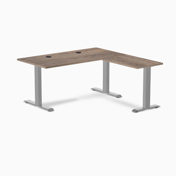 Natural walnut laminate L-shape office desk with gray steel frame and grommets.