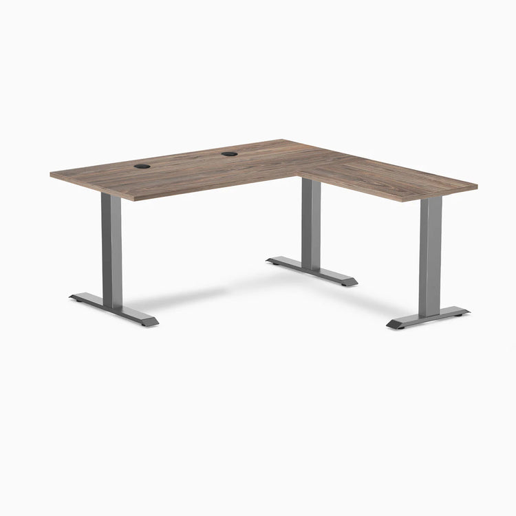Desky Zero L-shape office desk with a natural walnut laminate top, grommets, and space gray steel frame.