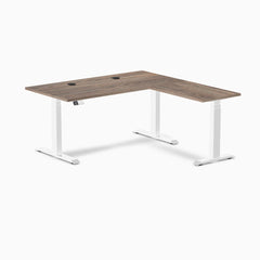 Desky L-Shape Laminate Sit Stand Desk in Natural Walnut with white frame and grommets.