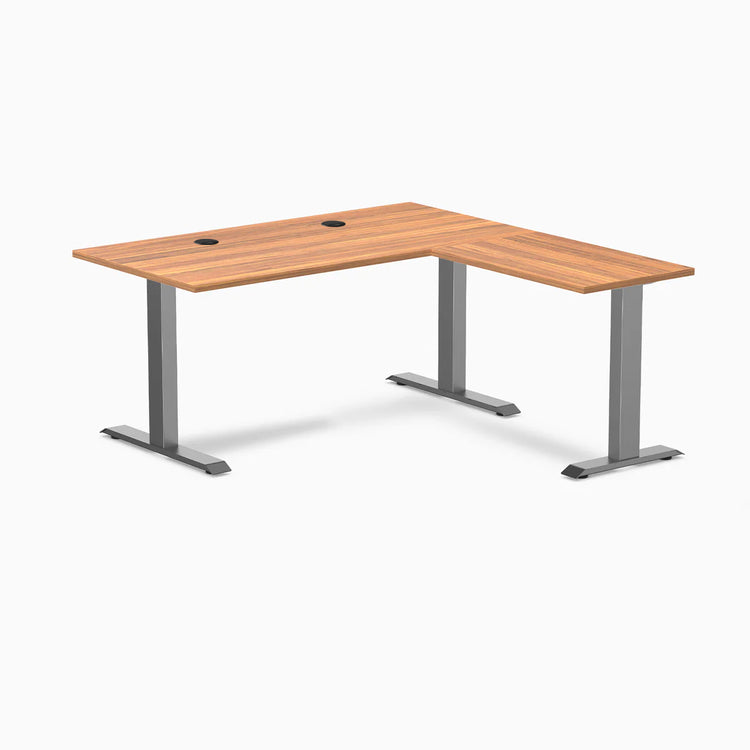 Prime Oak laminate L-shape office desk with Space Gray steel frame and grommets.