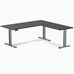 Desky L-Shape Laminate Sit Stand Desk in Burnished Wood with Space Gray frame and grommets.