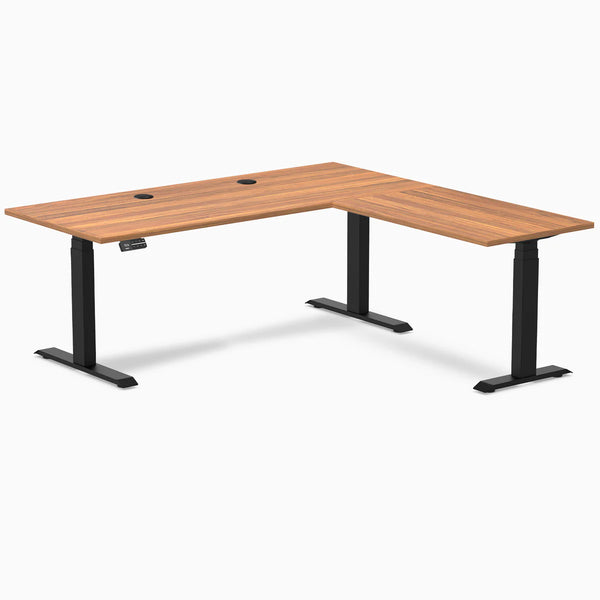 Prime Oak L-Shape Laminate Sit Stand Desk with matte black frame and grommets.