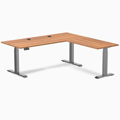 Prime Oak Desky L-Shape Laminate Sit Stand Desk with Space Gray frame and grommets.
