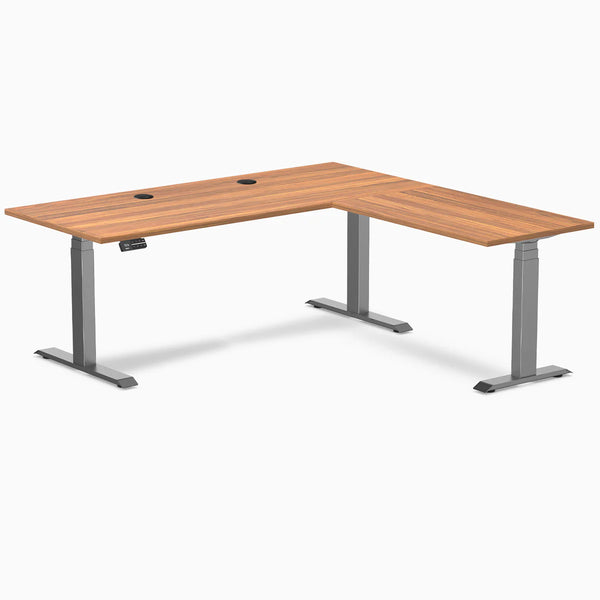 Prime Oak Desky L-Shape Laminate Sit Stand Desk with Space Gray frame and grommets.