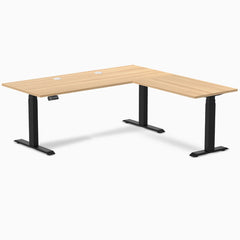 Desky L-Shape Laminate Sit Stand Desk in Sublime Teak with Matte Black frame and grommets.