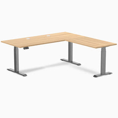 Desky L-Shape Laminate Sit Stand Desk in Sublime Teak with Space Gray frame and grommets.