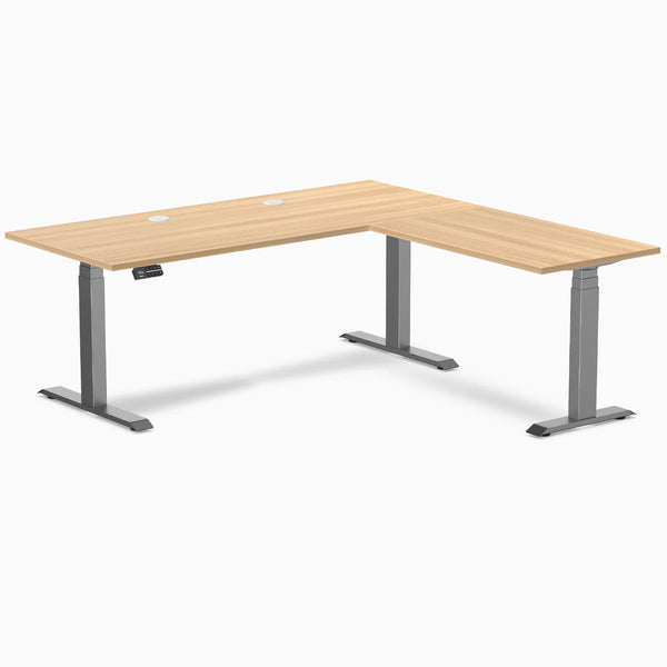 Desky L-Shape Laminate Sit Stand Desk in Sublime Teak with Space Gray frame and grommets.