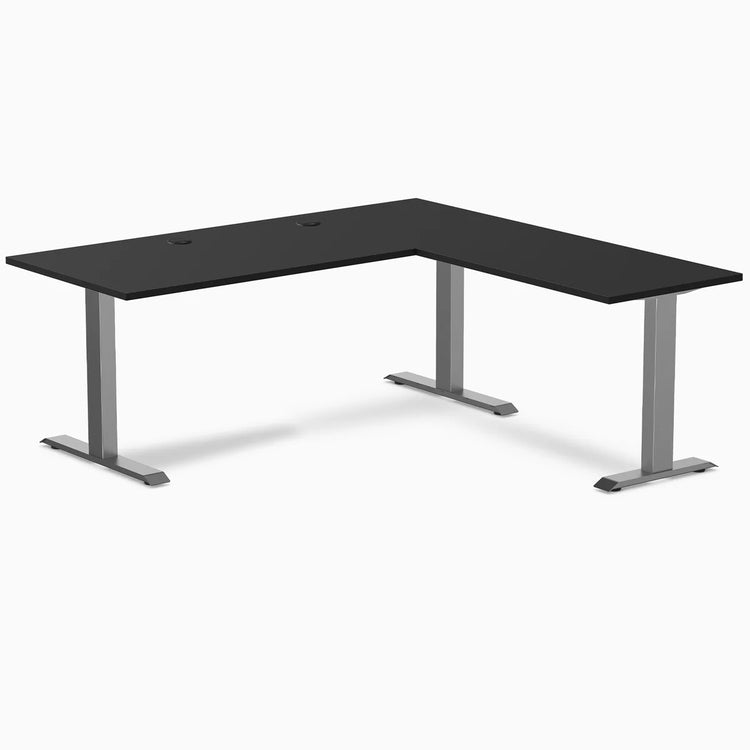 Black laminate L-shape office desk with space gray steel frame and grommets.