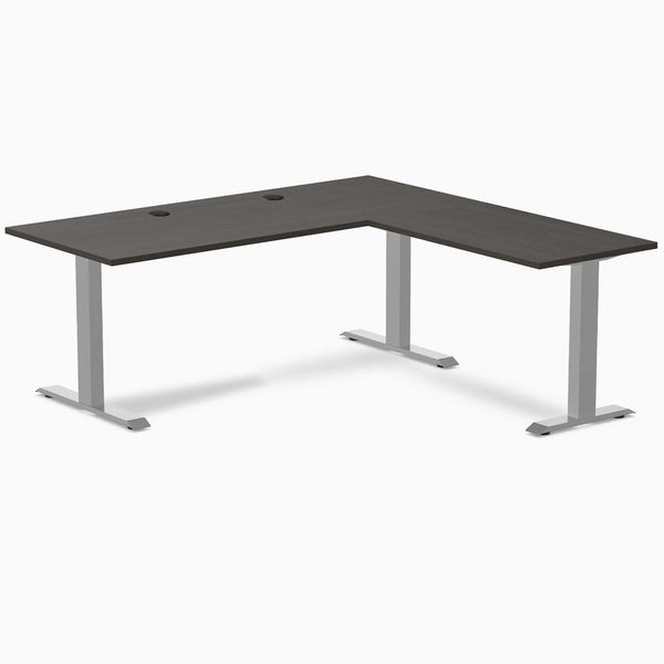 Burnished wood laminate L-shape office desk with gray steel frame and grommets.