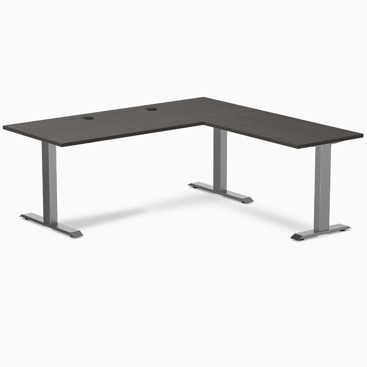 Burnished wood laminate L-shape office desk with space gray steel frame and grommets.