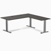 Burnished wood laminate L-shape office desk with space gray steel frame and grommets.