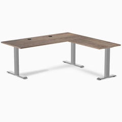Natural walnut L-shape office desk with gray steel frame and grommets.