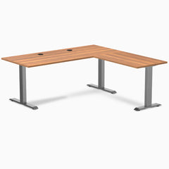 Prime Oak Desky Zero Laminate L-shape office desk with Space Gray steel frame and grommets.