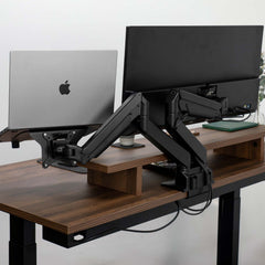 Black Desky Dual Monitor Arm supporting a laptop and monitor on a dark wood desk.