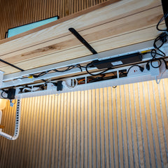 White Desky Integrated Cable & Power Channel with power outlets, neatly organizing cables under a light wood desk.
