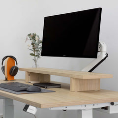 White Desky Single Monitor Arm holding a black Philips monitor on a light wood desk with a matching monitor riser.