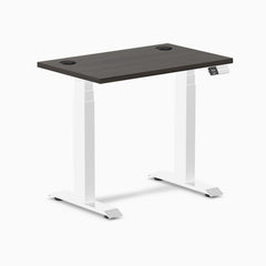 Desky Dual Mini sit-stand desk with burnished wood top, white frame, and grommets.