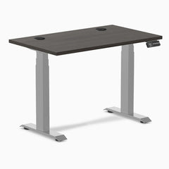 Desky Dual Mini sit-stand desk, 40x24 inch burnished wood top with grommets, gray frame.