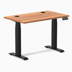 Desky Dual Mini sit-stand desk with Prime Oak 40x24 inch top, black grommets, and matte black legs.