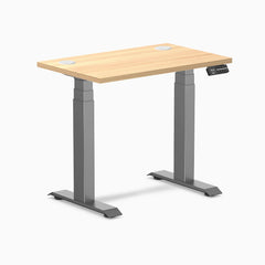 Desky Dual Mini sit-stand desk with Sublime Teak 32x20 inch top, grommets, and Space Gray frame.