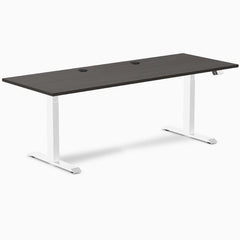 Desky Dual sit-stand desk with burnished wood laminate top, two grommets, and white frame.