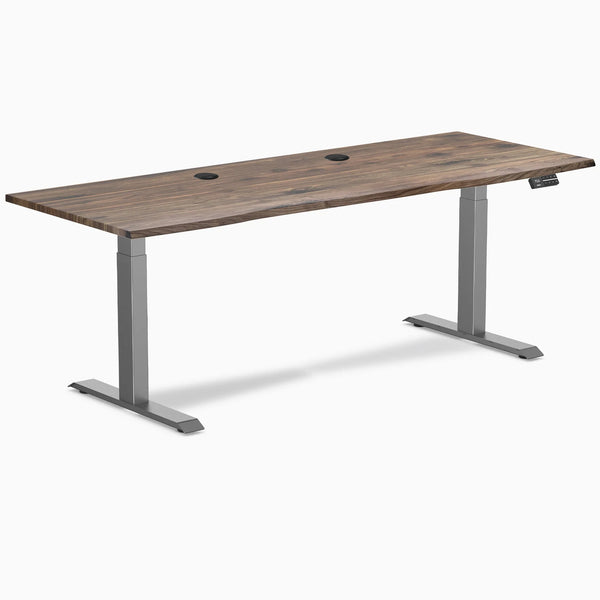 Desky Dual Laminate Sit Stand Desk with Natural Walnut top, Space Gray frame, and two grommets.