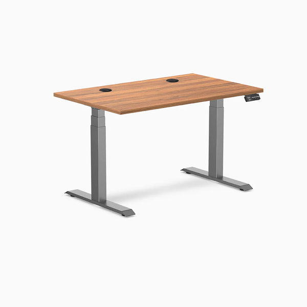 Desky Dual sit-stand desk with Prime Oak laminate top, Space Gray frame, and two grommets.