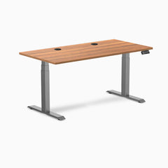 Desky Dual Prime Oak laminate sit-stand desk, 59.1x29.5 inches, with two grommets and Space Gray frame.