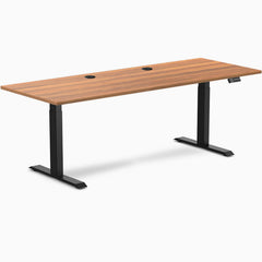Prime Oak Desky Dual Laminate Sit Stand Desk, 78.7x29.5 inches, with two grommets and matte black frame.
