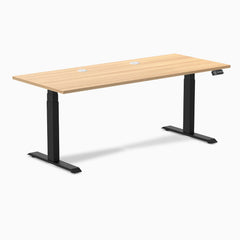 Desky Dual sit-stand desk with Sublime Teak laminate top, two grommets, and matte black frame.