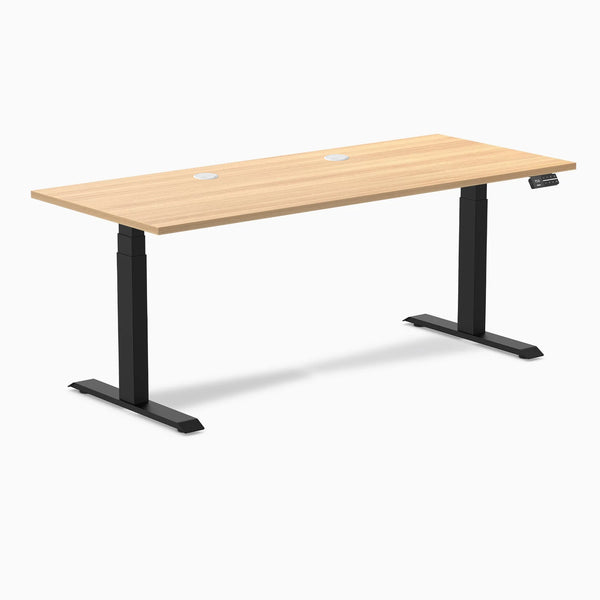 Desky Dual sit-stand desk with Sublime Teak laminate top, two grommets, and matte black frame.