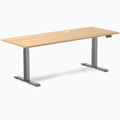 Desky Dual sit-stand desk with Sublime Teak laminate top, Space Gray frame, and grommets.