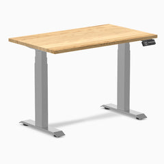Desky Dual Mini 40x24 inch White Oak hardwood sit-stand desk with gray frame and control panel.