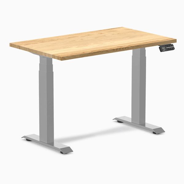 Desky Dual Mini 40x24 inch White Oak hardwood sit-stand desk with gray frame and control panel.